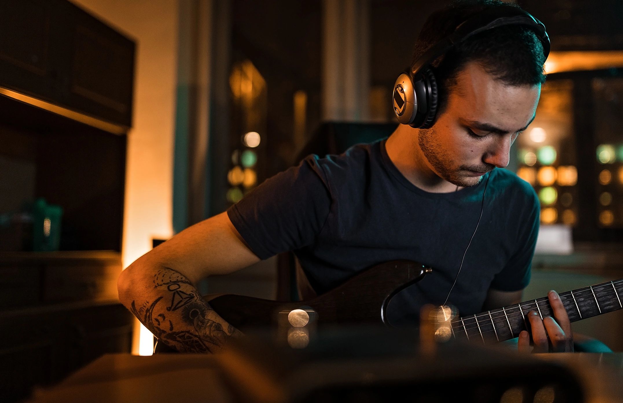 Musician recording guitar on a laptop in a home studio
