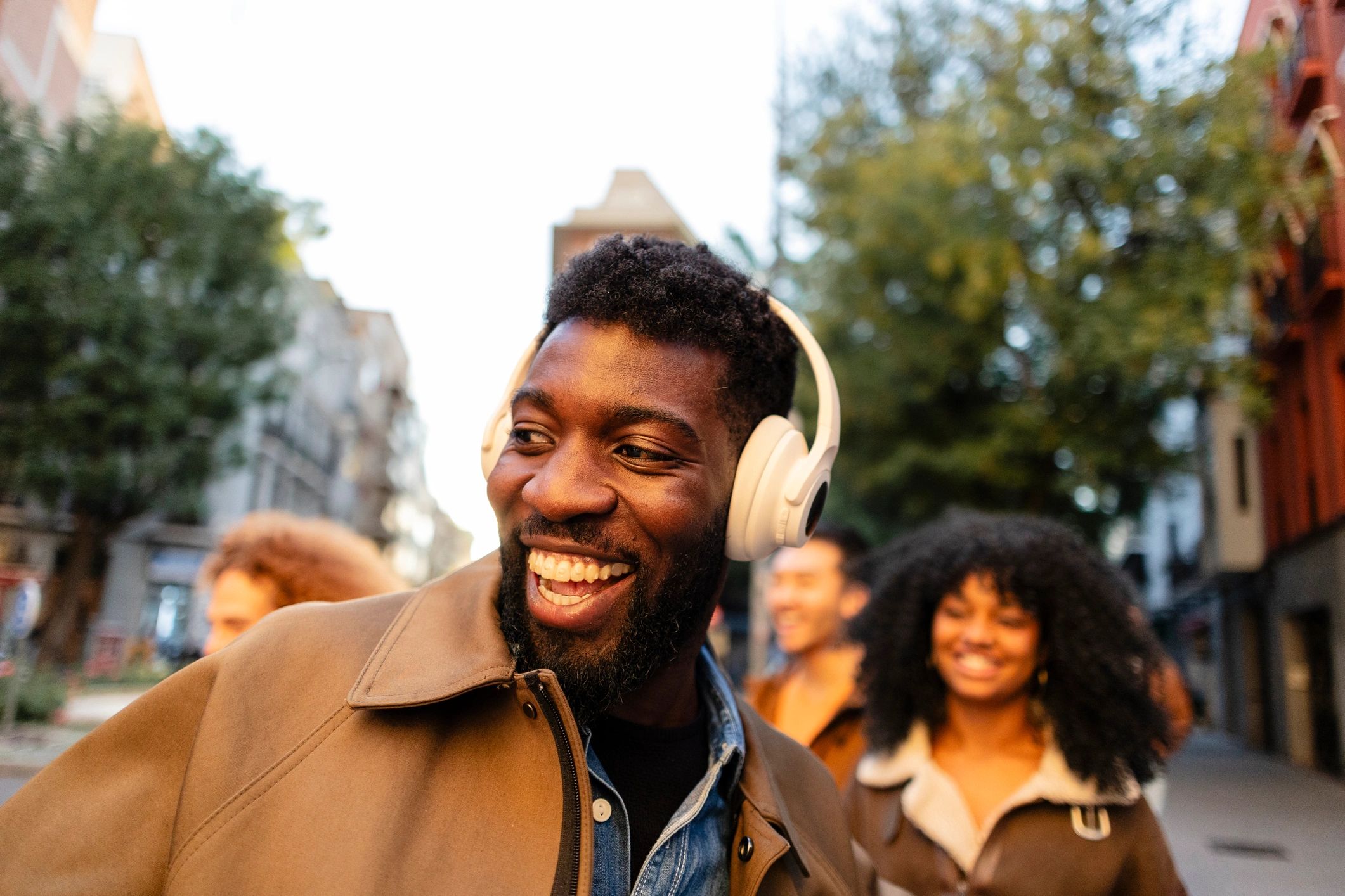Young man wearing headphones smiling while walking in the city